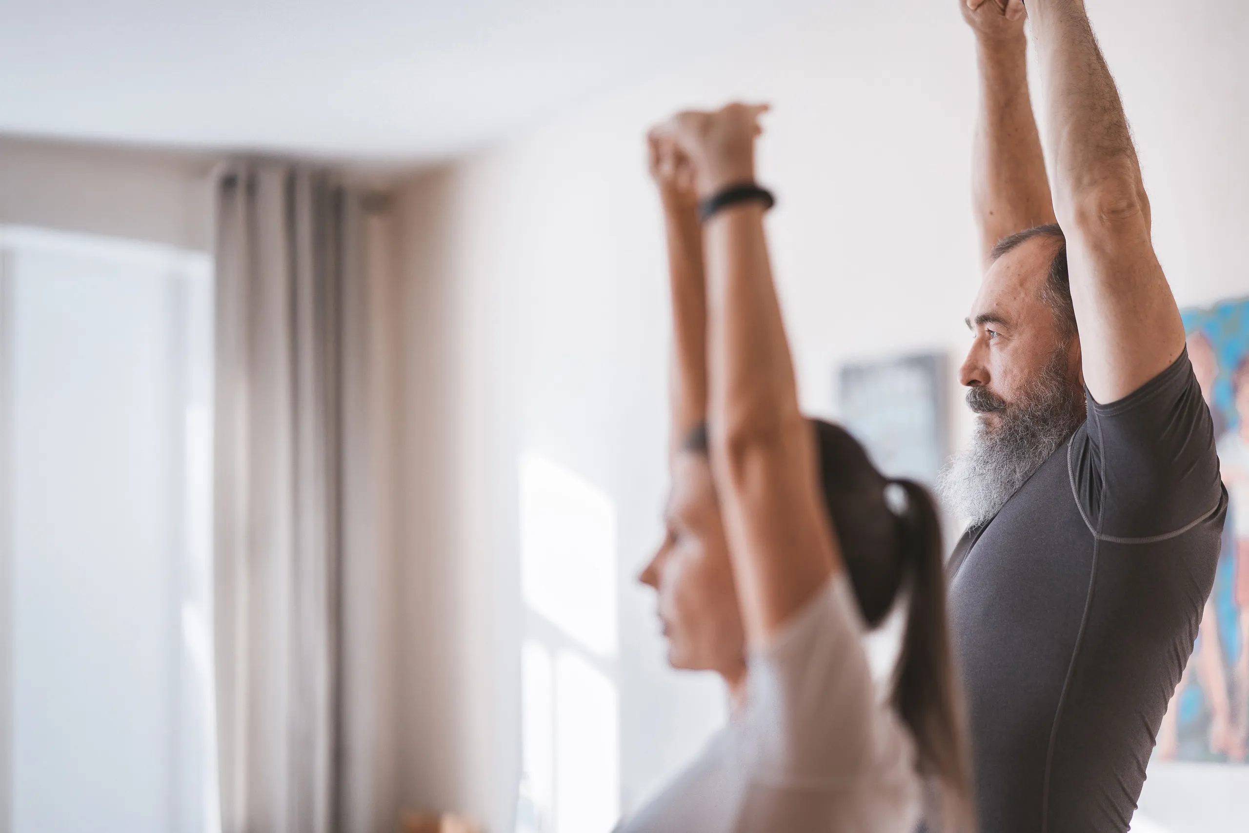 Two study participants stretching with arms raised during an at-home fitness session
